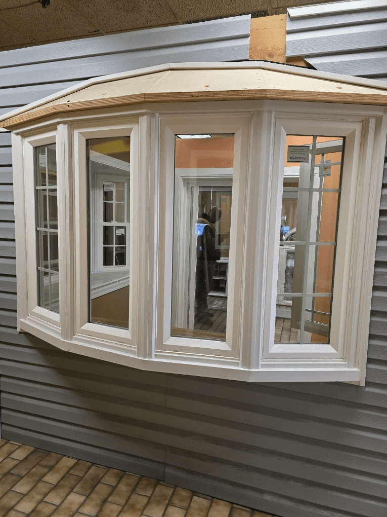 Bay window unit with white trim and grilles, on display in the Star Windows Doors Siding showroom
