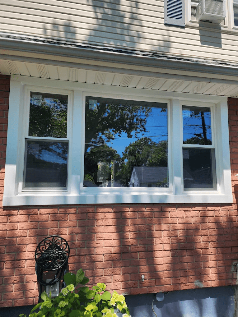 New double-hung and picture windows with fresh white trim, installed on a brick home in North Jersey